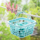 Teal laundry basket with clothespins on a clothesline against a blurred green background