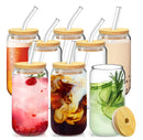 Six clear glass mason-style drinking cups with bamboo lids and clear curved straws, shown filled with different beverages on a white background.