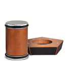 A wooden cylindrical drum with a silver metal drumhead and black trim, shown next to its matching hexagonal wooden stand on a white background.