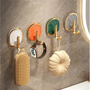 Set of decorative wall hooks with different colored backings on a marble wall.