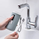 Person holding a striped travel mug and toothbrush next to a sink with a faucet.